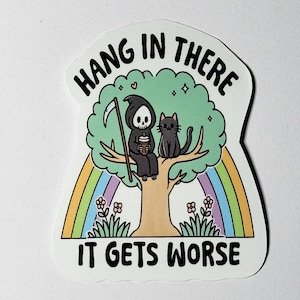 May include: A white sticker with a black and white illustration of a grim reaper and a black cat sitting in a green tree with a rainbow behind them. The text "Hang in there it gets worse" is written in black on the sticker.