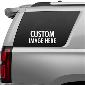 May include: A silver vehicle rear side window featuring a black decal area with the white text CUSTOM IMAGE HERE centered in the middle. The window is tinted dark and positioned on the side of a light-colored car body with a red taillight visible.