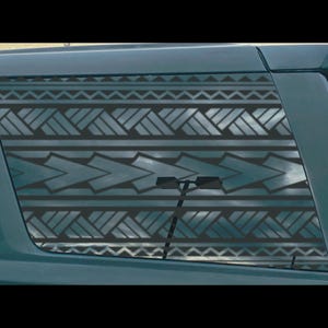 May include: A car window with a decorative tribal pattern in shades of gray and black. The design features geometric shapes and arrow-like elements, creating a textured appearance. The window is part of a dark-colored vehicle.