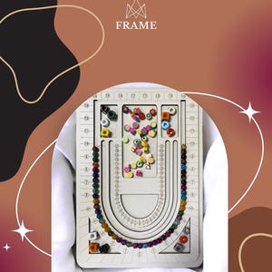 May include: A white wooden jewelry design board with a U-shaped channel and various compartments filled with colorful beads. The board has measurement markings and is designed for jewelry making. The word "FRAME" is at the top.