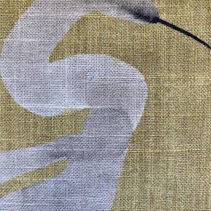 May include: Close-up of a fabric with a white bird design on a golden-yellow background. The bird's body is white, with a gray head and a long black beak. The fabric has a textured appearance.