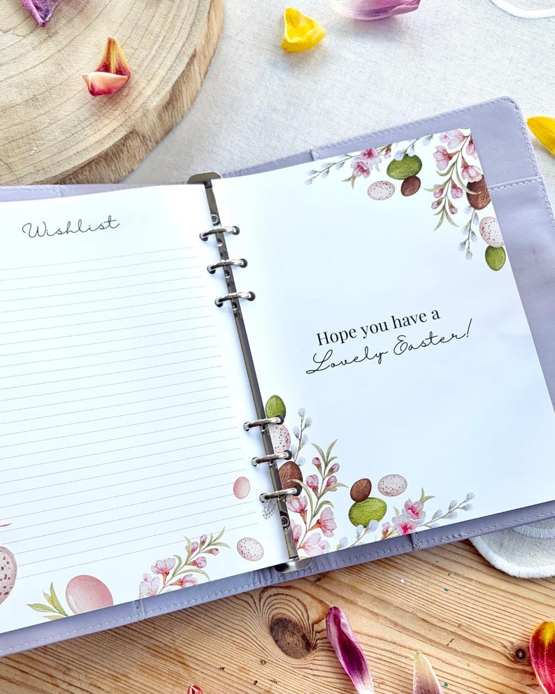 May include: Open lavender binder with lined pages and the word "Wishlist" on the left. The right page has the text "Hope you have a Lovely Easter!" with floral and egg illustrations. The binder is open on a wooden surface.