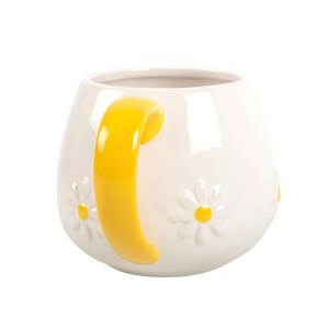 May include: White ceramic mug with a yellow handle and embossed daisy flowers. The mug has a rounded shape and a glossy finish. The daisies have yellow centers. A charming and cheerful design for a coffee or tea cup.