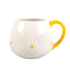 May include: White ceramic mug with a yellow handle. The mug features embossed daisy flowers with yellow centers. The mug has a rounded shape and is suitable for hot or cold beverages.