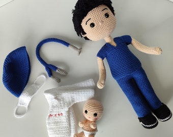 May include: A crocheted doll dressed in blue scrubs, with black hair and black shoes, and a matching blue cap. Accessories include a white lab coat with red text, a stethoscope, a face mask, and a small baby doll.