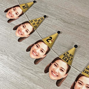 May include: A gold glitter birthday banner with a photo of a person's face on each flag. The flags have the text "Legal AF", "21", "21", "21 21", "21 21 21", "21", "In My Adult Era", and "Ah, Car" printed on them.