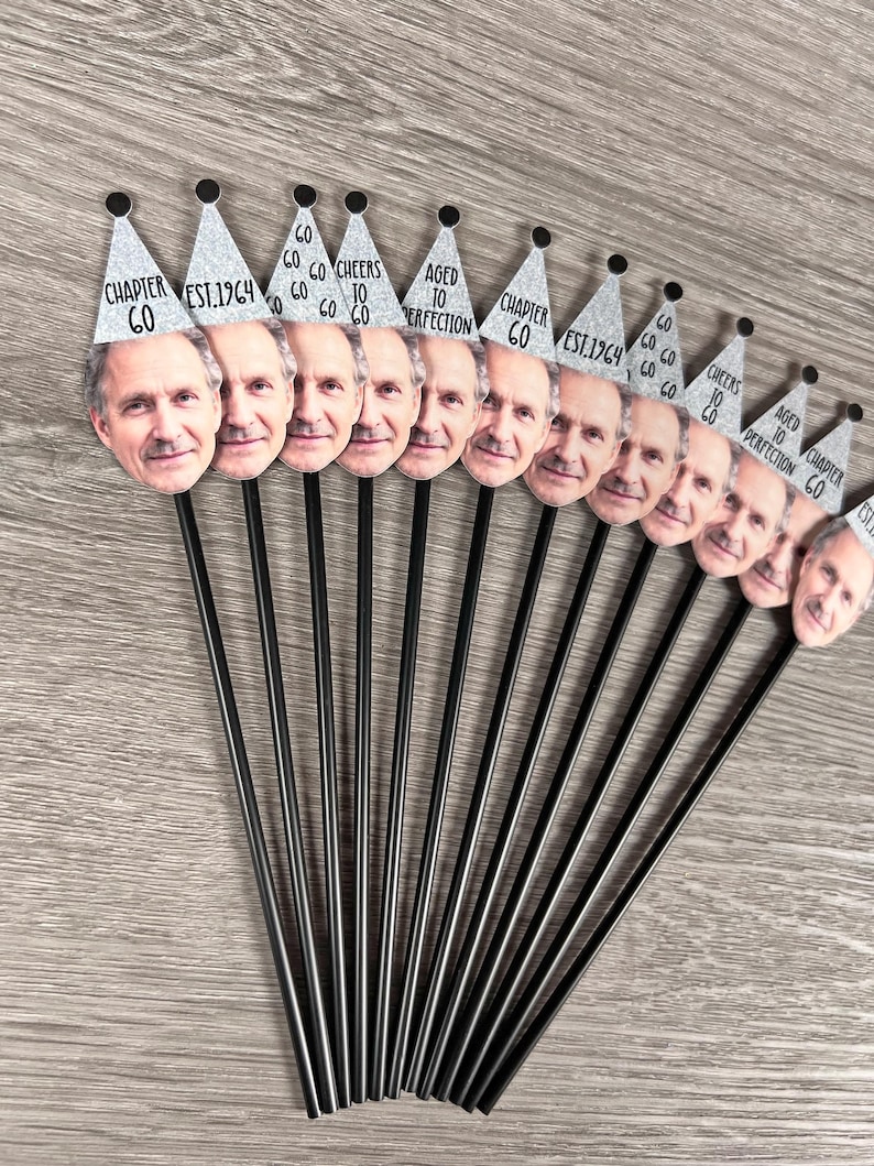 May include: A set of 10 silver party hats with black text on top of black straws. The hats have different text on them, including 'Chapter 60', 'Est. 1964', 'Aged to Perfection', and 'Go Go Go Cheers To Go Go Go'.