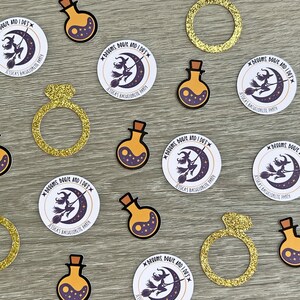 May include: A collection of party decorations, including gold glitter rings, potion bottles, and circular stickers. The stickers feature a witch on a broomstick in front of a crescent moon, with the text "Brooms, Booze, and I Do's" and "Jessica's Bachelorette Party."