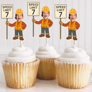 May include: Three cupcakes with white frosting, each topped with a cartoon figure of a child dressed as a construction worker holding a "SPEED LIMIT 7" sign. The cupcakes are in paper liners.