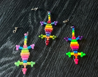 Può includere: Tre portachiavi a forma di lucertola con perline colorate. Ogni lucertola è realizzata con perline arcobaleno e ha uno stringa nera attaccata a un portachiavi argentato.