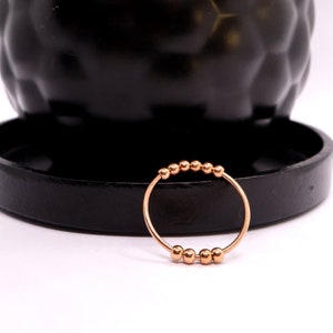 May include: A rose gold ring with a row of small, round beads.