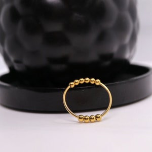 May include: A gold ring with a row of small, round beads.
