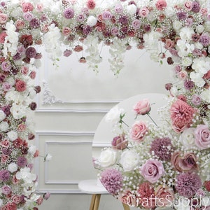 May include: An artificial flower arch featuring a mix of pink, white and cream roses, baby's breath and other small blooms. The arch is ideal for a wedding or other special occasion.