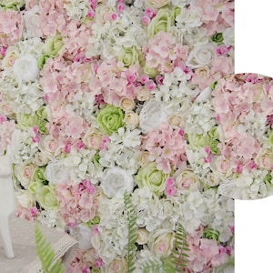 May include: A wall covered in a variety of artificial flowers, including white, pink, and green roses, hydrangeas, and other blooms. The flowers are arranged in a dense, lush pattern, creating a beautiful and realistic floral backdrop.