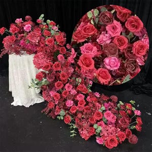 Puede incluir: Un gran arreglo floral hecho de rosas rojas y rosas, con vegetación, para una decoración de boda o evento.