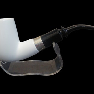 May include: A white ceramic pipe with a black and silver band and a black ebonite stem. The pipe is on a clear acrylic stand.