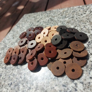 Puede incluir: Un montón de anillos de cuero en varios tonos de marrón, tostado y negro. Los anillos están apilados sobre una superficie de granito gris.