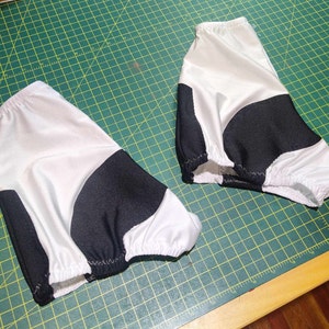 May include: Two white and black fabric arm warmers with a gathered elastic edge.