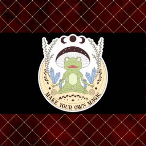 May include: A sticker featuring a green frog meditating with a mushroom cap, set against a crescent moon with crystals. The text "MAKE YOUR OWN MAGIC" is written around the moon. The background is black with a red diamond pattern.