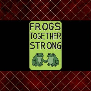 May include: A rectangular sign with the words "FROGS TOGETHER STRONG" in black capital letters on a light green background. Two green cartoon frogs hold hands below the text. The background is black with a red diamond pattern.