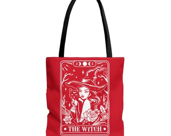 Puede incluir: Bolsa de tela roja con una ilustración blanca de una bruja sosteniendo un gato negro. La ilustración está en el estilo de una carta de tarot e incluye el texto "THE WITCH".