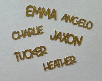 May include: Gold glitter letters spelling out the names Emma, Angelo, Charlie, Jaxon, Tucker, and Heather.