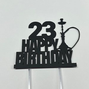 May include: A black cake topper featuring the number 23 and the text HAPPY BIRTHDAY in a bold font, accompanied by a silhouette of a hookah pipe. The design is mounted on two clear, transparent plastic sticks for insertion into a cake.