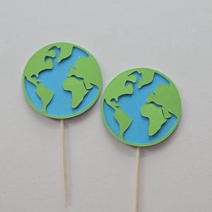 May include: Two green and blue earth globe cupcake toppers with wooden picks.