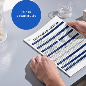 May include: A white sheet of paper with the text "TEAM MEETING AGENDA" printed in black. The agenda includes sections for "Welcome & Team Updates", "Action Items & Progress", "Team Updates & Time Tracking", "Open Planning & To Do Items", "Discussion Items & Agreements", and "Next Steps & Follow Up".
