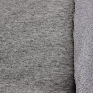 Könnte beinhalten: Ein Stoff mit zwei Texturen, bestehend aus einer grauen Jersey-Strickseite mit feiner, gesprenkelter Optik und einer kontrastierenden Seite aus weichem, flauschigem, hellgrauem Fleece mit dichtem, pelzigem Flor, die beide Seiten zeigt.