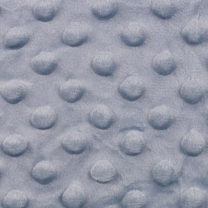 Könnte beinhalten: Nahaufnahme eines hellblauen Stoffes mit einem strukturierten, gepunkteten Muster. Das Plüschmaterial hat ein samtiges Aussehen, mit gleichmäßig verteilten, erhabenen kreisförmigen Erhebungen auf der Oberfläche. Der Stoff scheint eine gemütliche Decke zu sein.