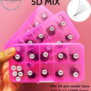 May include: Pink plastic storage case with multiple compartments filled with black eyelash extensions. The case has labels indicating the length of the lashes in millimetres. The text on the case reads "5D MIX", "Mix 5d pro made fans", "mix 8-13 (1000 fans)", and "mix 9-15 (1000 fans)".