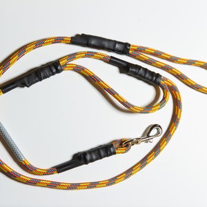 May include: A yellow, blue, and red rope dog leash with black tape accents and a silver clip.