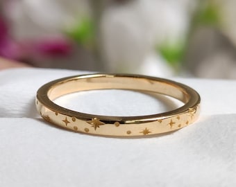 Op de afbeelding: Een dunne gouden ring met een delicaat ontwerp van sterren en stippen rond de hele band.
