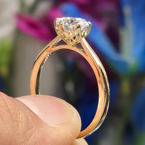 May include: A gold engagement ring with a round, clear diamond set in a delicate, floral-inspired setting.