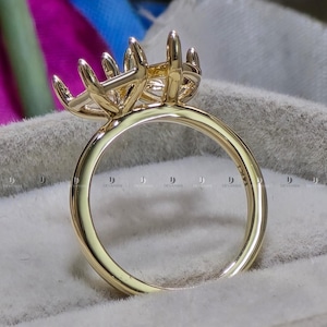 May include: A gold ring featuring a multi-prong setting designed to hold a gemstone. The interior of the smooth, polished gold band is clearly stamped with the text 14K, indicating the metal purity of the jewelry piece.