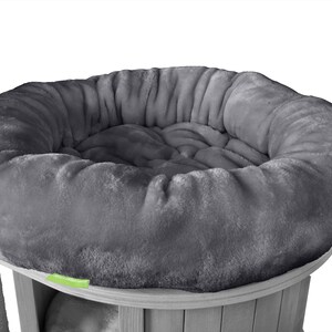K&ouml;nnte beinhalten: Graues, pl&uuml;schiges Katzenbett mit rundem, gepolstertem Design. Das Bett ist Teil einer Kratzbaumstruktur, mit einem Sisal-Kratzpfosten auf der linken Seite. Das Bett ist aus weichem, flauschigem Material.