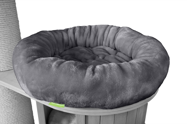 K&ouml;nnte beinhalten: Graues, pl&uuml;schiges Katzenbett mit rundem, gepolstertem Design. Das Bett ist Teil einer Kratzbaumstruktur, mit einem Sisal-Kratzpfosten auf der linken Seite. Das Bett ist aus weichem, flauschigem Material.