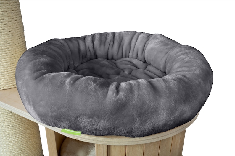 K&ouml;nnte beinhalten: Ein graues, pl&uuml;schiges Katzenbett mit runder Form, das auf einem Katzenbaum aus Holz steht. Das Bett hat ein weiches, einladendes Aussehen, perfekt f&uuml;r den Komfort der Katze. Der Katzenbaum hat eine nat&uuml;rliche Holzoberfl&auml;che.