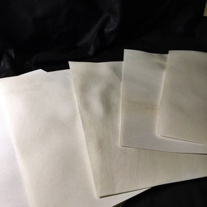 May include: Four white sheets of paper stacked on top of each other. The paper is slightly textured and has a subtle off-white color.