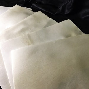 May include: A stack of white, textured paper sheets. The sheets are folded in half and stacked on top of each other.