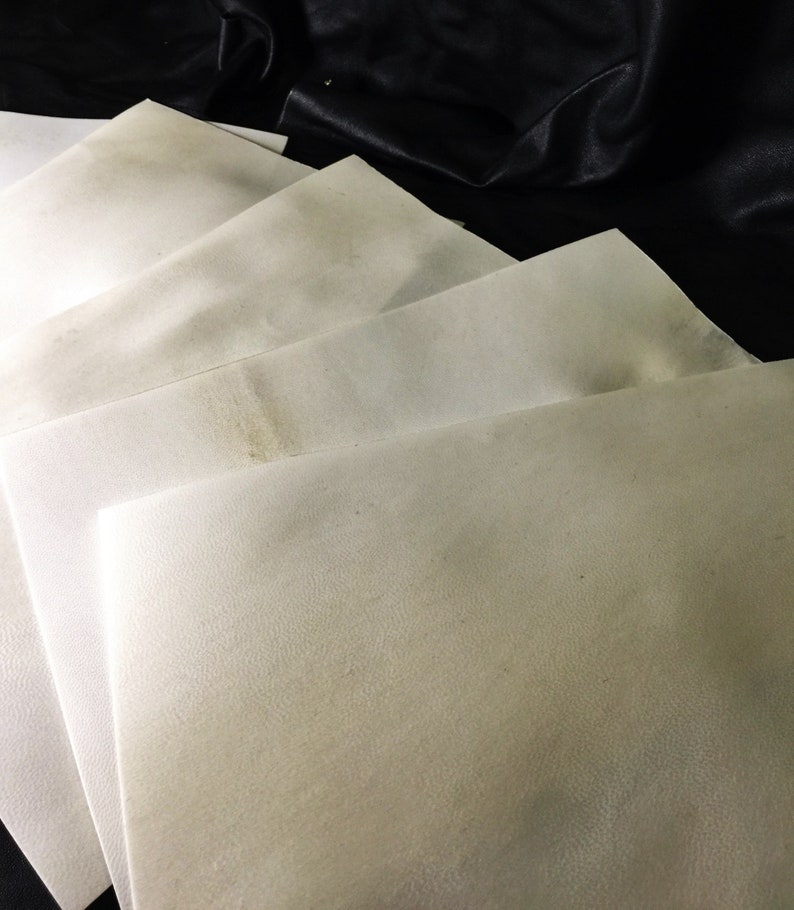 May include: A stack of white, textured paper sheets. The sheets are folded in half and stacked on top of each other.