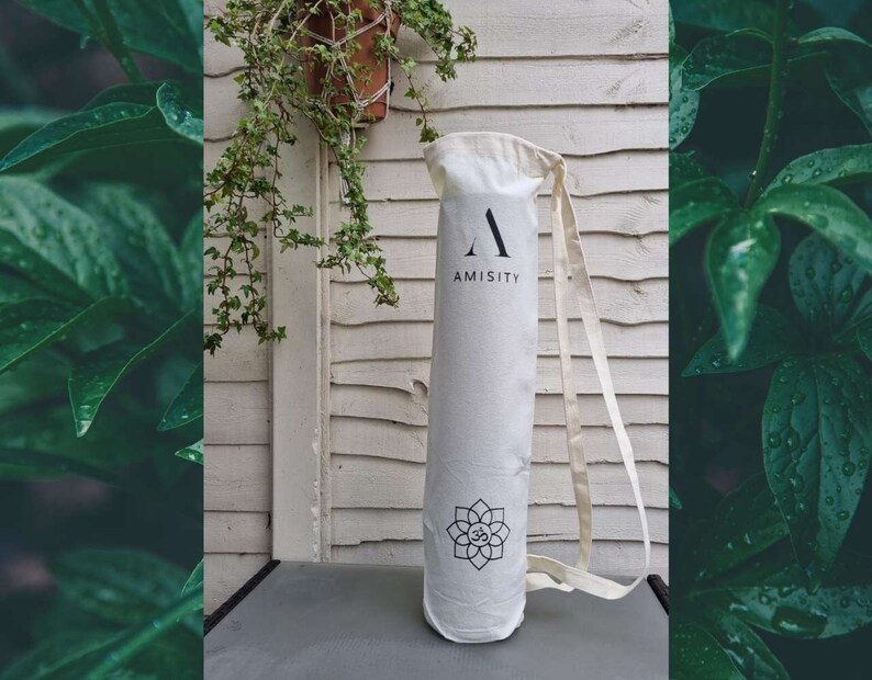 May include: White canvas yoga mat bag with a black strap and the word "AMISITY" printed on the front. The bag has a black and white lotus flower design.