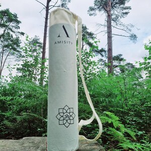 May include: A white yoga mat bag with a black logo that says "AMISITY" and a black and white Om symbol. The bag has a white strap.