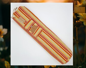 May include: A red, yellow, and white striped yoga mat bag with a small pocket and a brown leather tag that says "Amity".