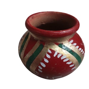 May include: A small, round, terracotta pot with a red exterior. The pot is decorated with gold, green, and white painted designs. The rim of the pot is also painted red.