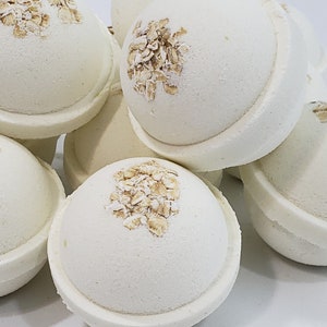 May include: A close-up of a pile of white bath bombs with a light brown oatmeal topping.