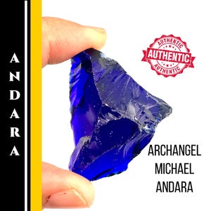 Puede incluir: Un vibrante cristal Andara azul profundo, sostenido entre dedos, con el texto "Archangel Michael Andara". Un sello rojo dice "Auténtico". El cristal tiene una forma rugosa e irregular y una superficie brillante.