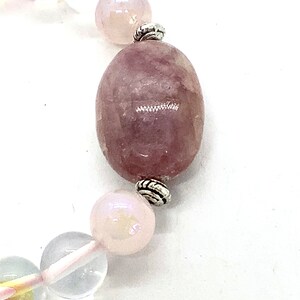May include: A pink and clear crystal bracelet with silver accents. The bracelet features a large oval-shaped pink crystal bead.
