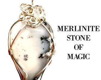 Puede incluir: Un colgante de piedra Merilinite con un alambre de plata. La piedra es blanca con inclusiones negras y grises. El colgante tiene un lazo en la parte superior para una cadena. El texto a la derecha dice: MERLINITE STONE OF MAGIC.